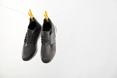 Photo of Stylish sneakers drying on washing line against light grey background, space for text