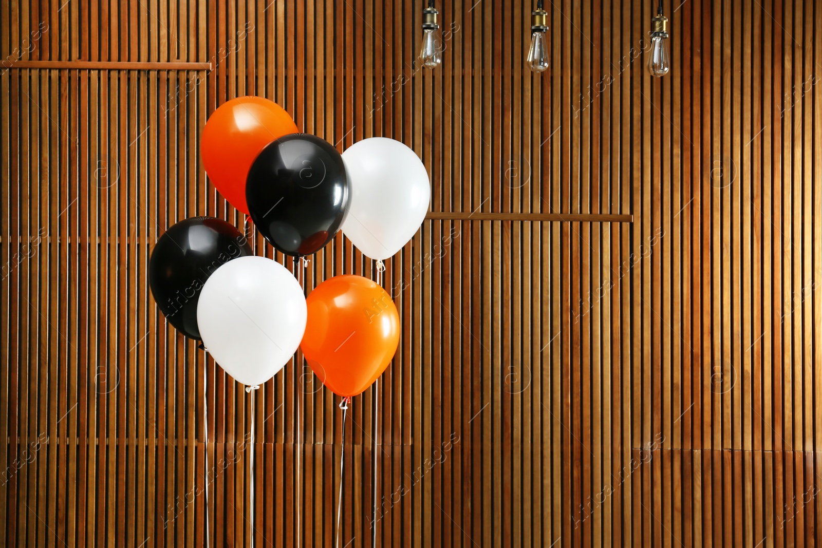 Photo of Colorful balloons against wooden wall, space for text. Halloween party