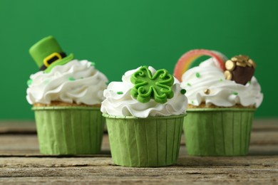 Photo of St. Patrick's day party. Tasty festively decorated cupcakes on wooden table, closeup