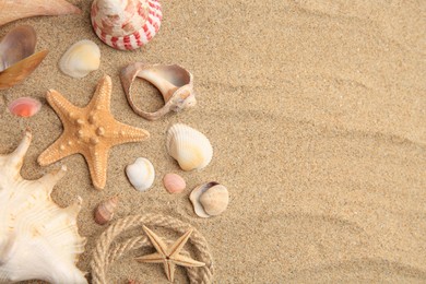 Photo of Beautiful sea stars, shells and rope on sand, flat lay. Space for text