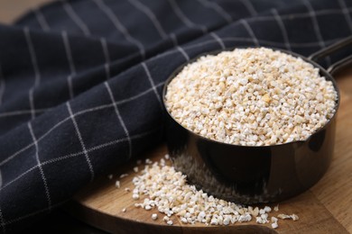 Photo of Raw barley groats in scoop on table, closeup. Space for text