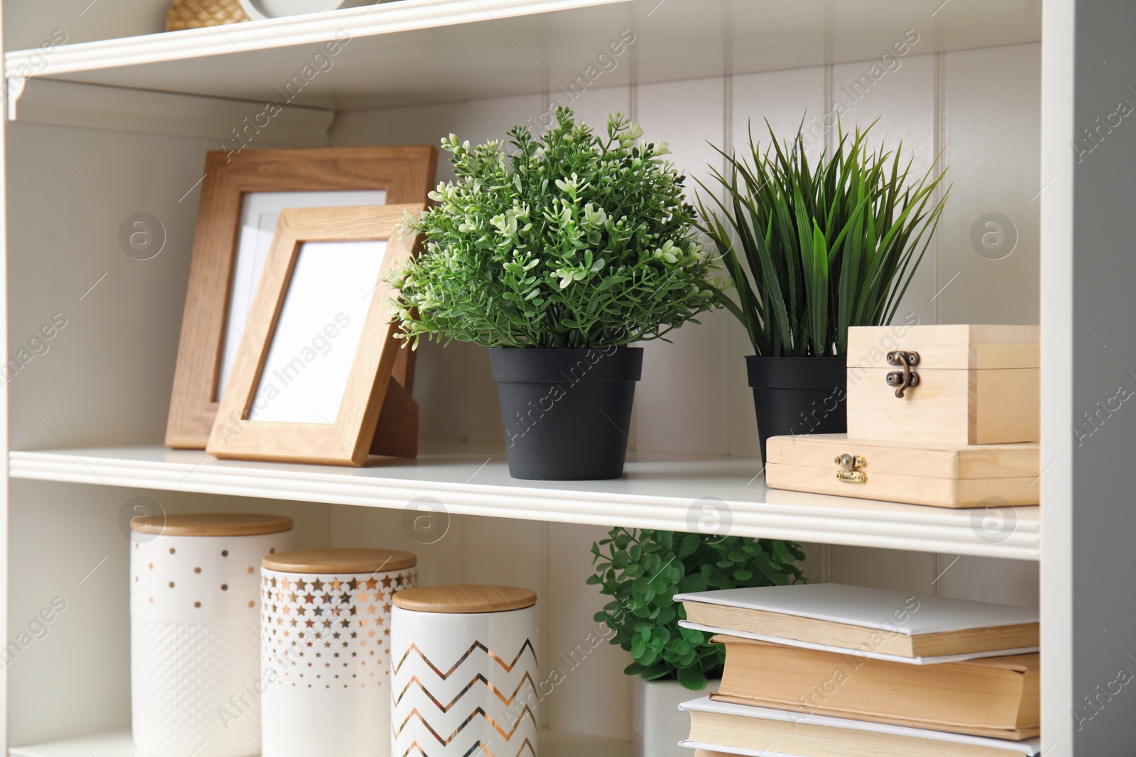 Photo of White shelving unit with plants and different decorative stuff