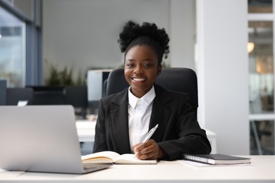 Photo of Happy woman working at table in office. Lawyer, businesswoman, accountant or manager