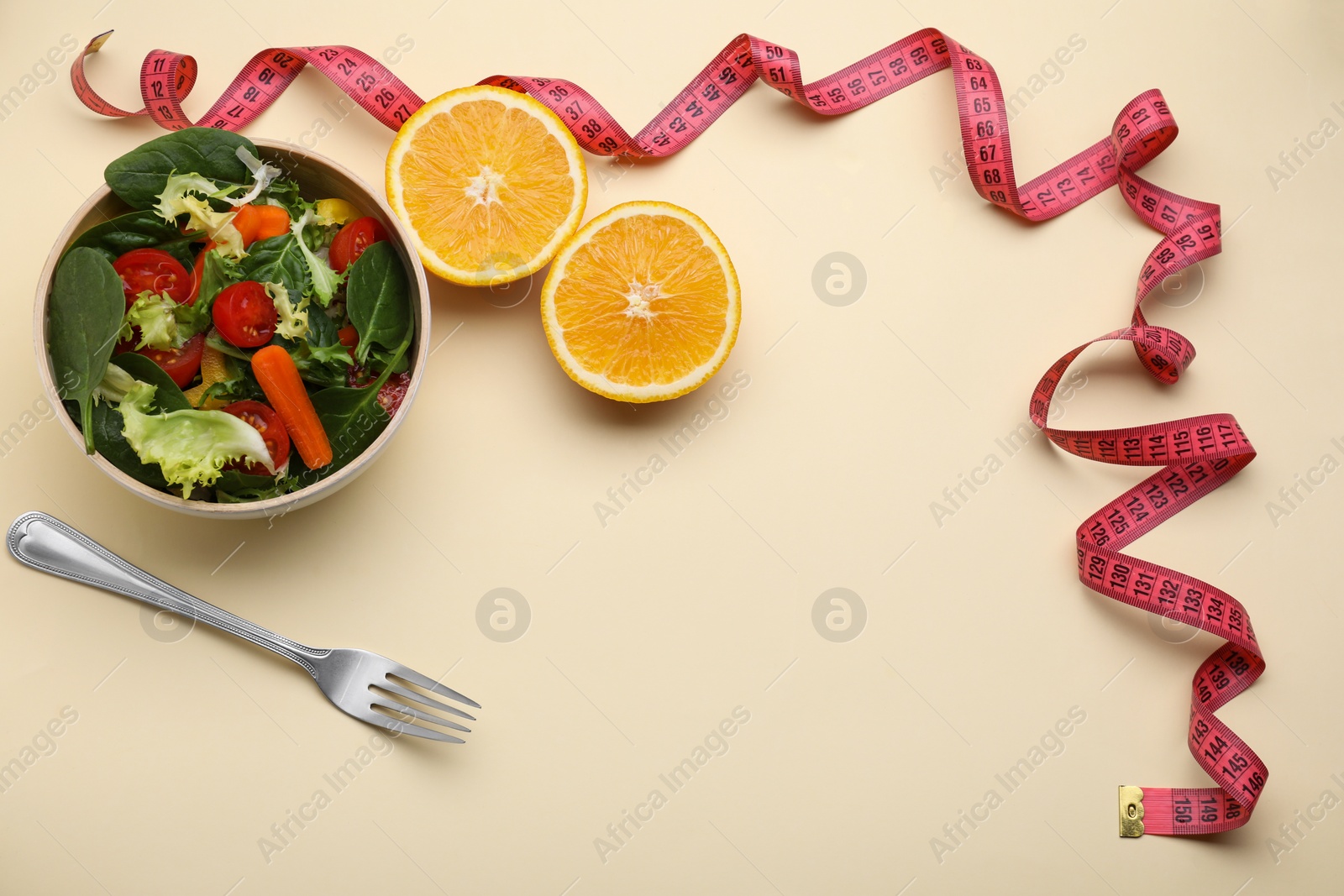 Photo of Measuring tape, salad, halves of orange and fork on yellow background, above view. Space for text