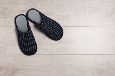 Photo of Pair of stylish slippers on white wooden floor, top view. Space for text