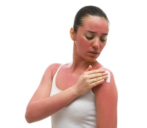 Woman applying cream on sunburn against white background