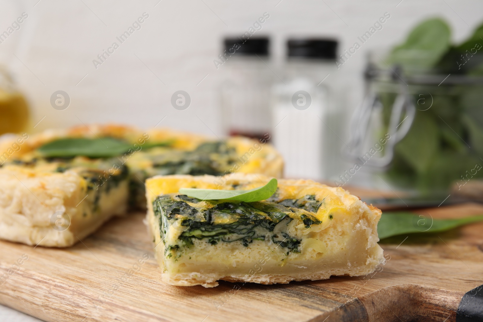 Photo of Piece of delicious pie with spinach on wooden board, closeup