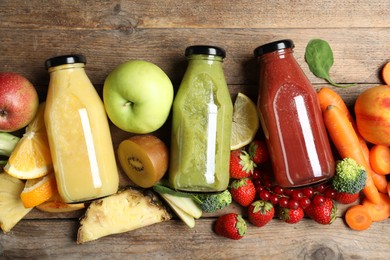 Photo of Bottles of delicious juices and fresh fruits on wooden table, flat lay