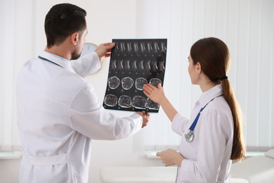 Professional orthopedist and his colleague examining X-ray picture in office