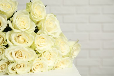 Photo of Luxury bouquet of fresh roses near white brick wall, closeup