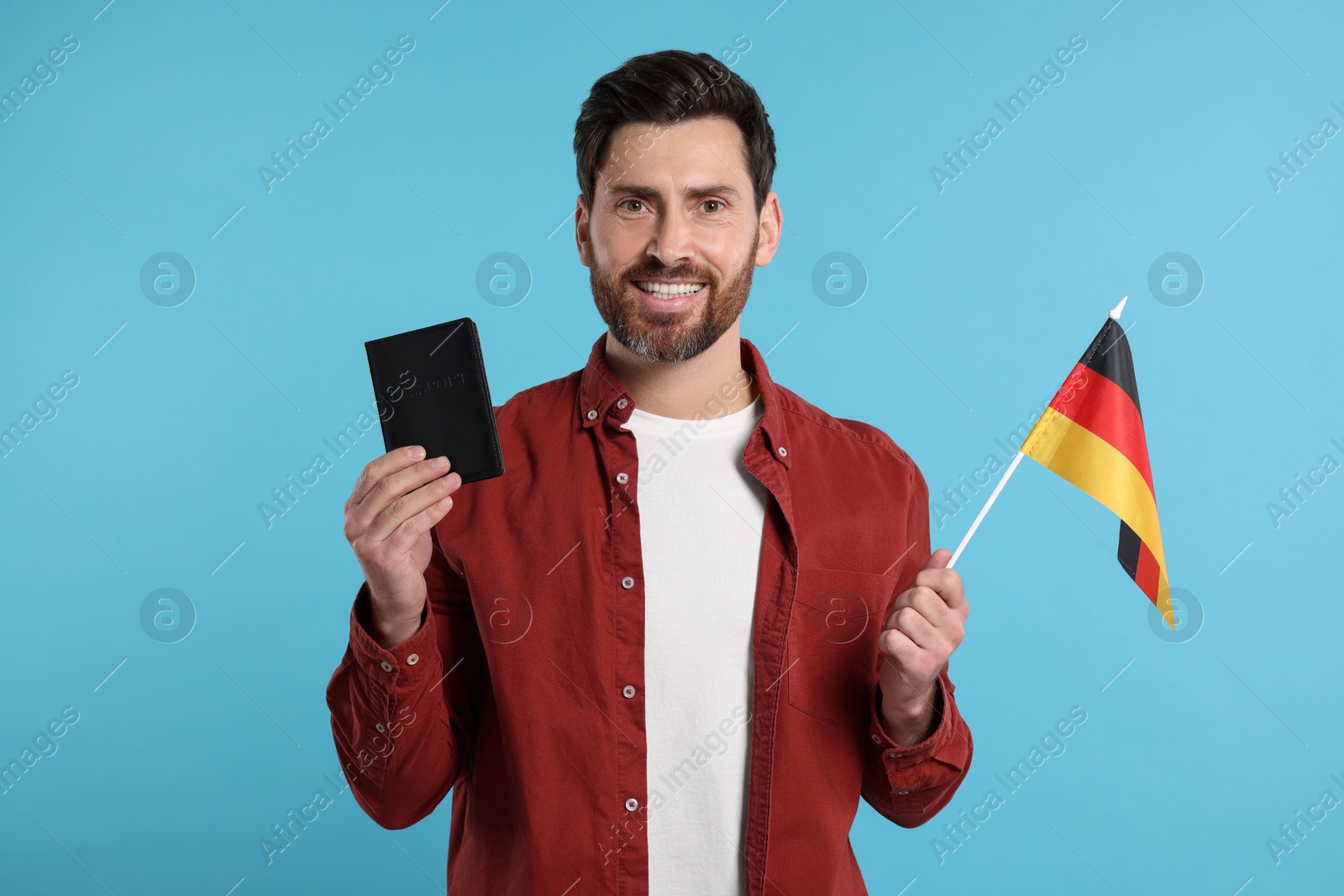 Photo of Immigration. Happy man with passport and flag of Germany on light blue background