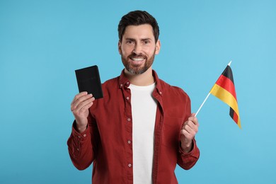 Immigration. Happy man with passport and flag of Germany on light blue background