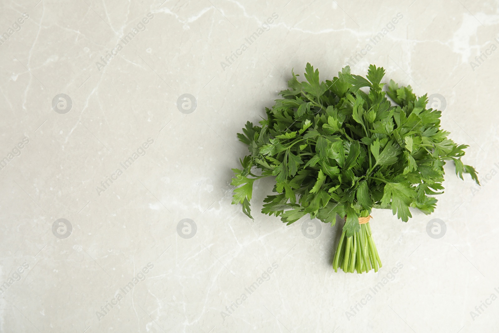 Photo of Bunch of fresh green parsley on light background, view from above. Space for text