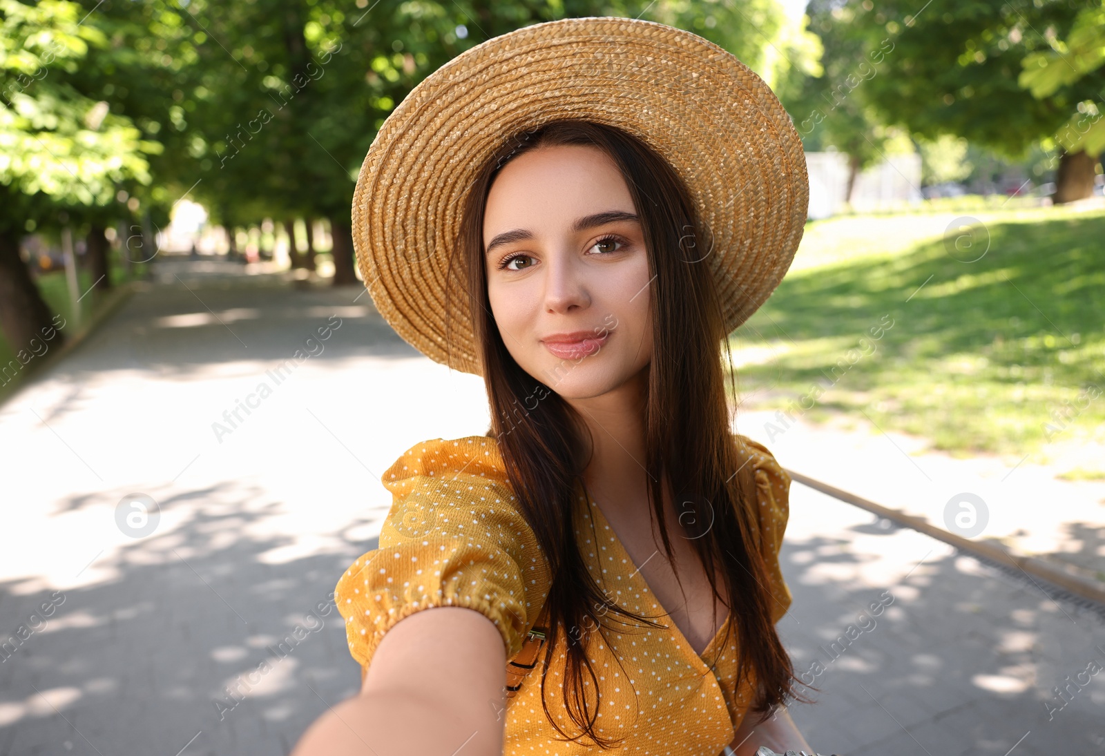 Photo of Travel blogger in straw hat takIng selfie outdoors
