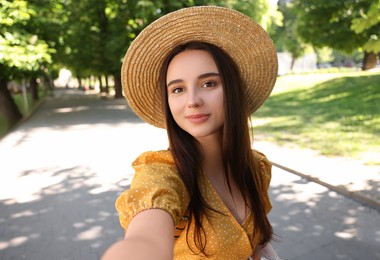 Travel blogger in straw hat takIng selfie outdoors