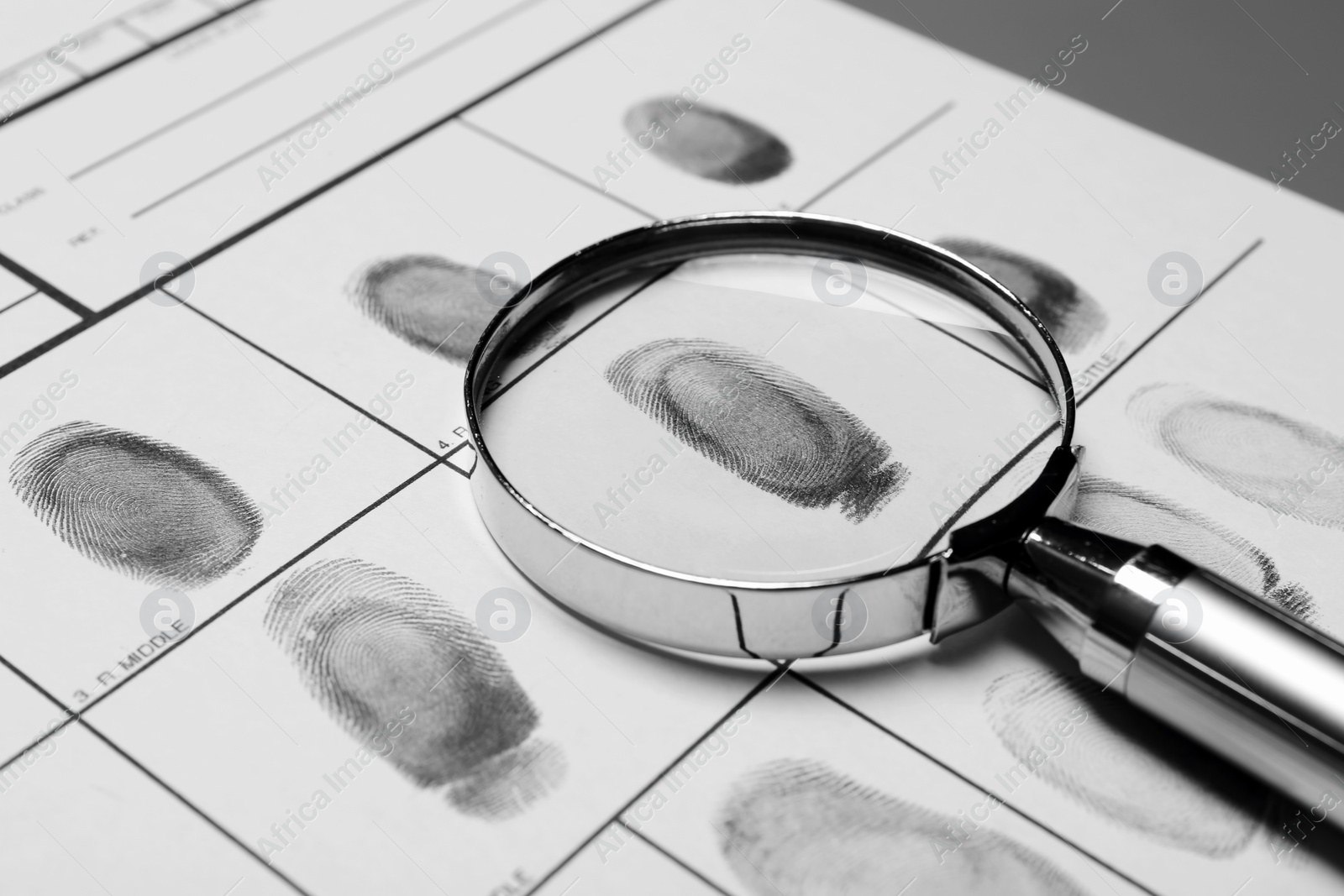 Photo of Magnifying glass and criminal fingerprint card, closeup