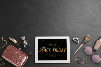Photo of Tablet with Black Friday announcement and stylish accessories on dark table, flat lay. Space for text