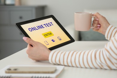 Photo of Woman taking online test on tablet at desk indoors, closeup