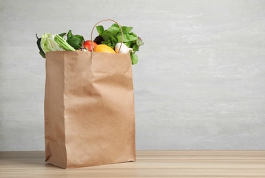 Photo of Paper bag with vegetables on table against grey background. Space for text