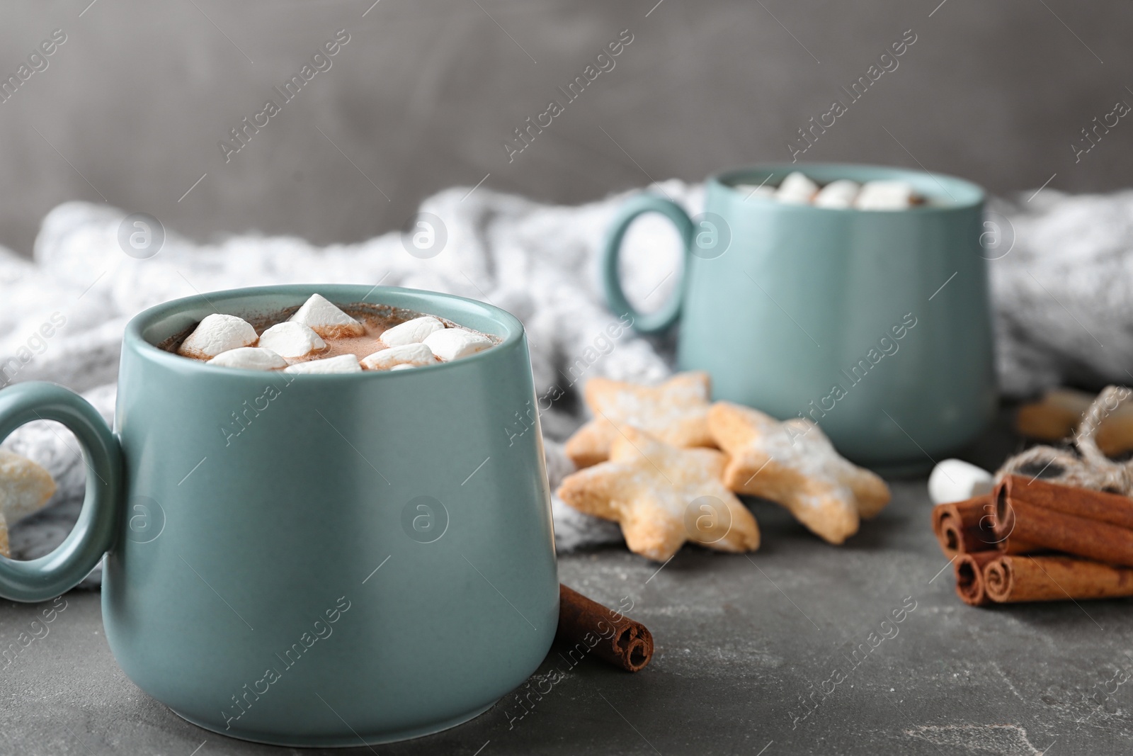 Photo of Composition with delicious cocoa drink in blue cups and blanket on grey table