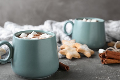 Composition with delicious cocoa drink in blue cups and blanket on grey table