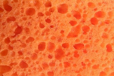 Photo of Clean orange sponge as background, top view