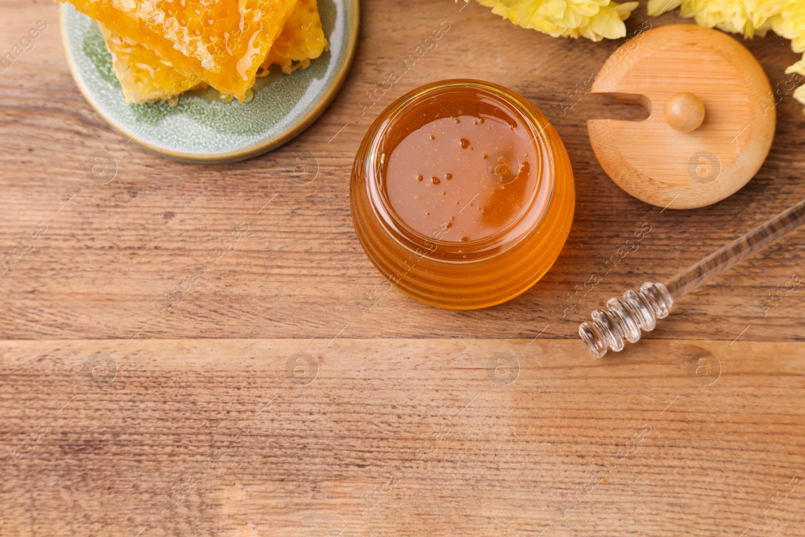 Photo of Sweet golden honey in jar and dipper on wooden table, flat lay. Space for text