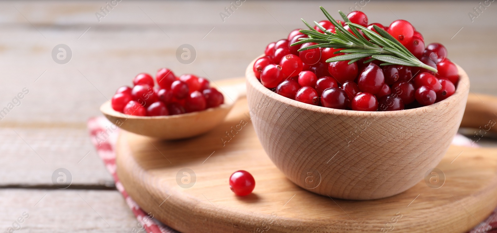 Photo of Fresh ripe cranberries and rosemary on wooden table, closeup