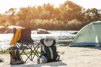 Set of equipment near camping tent on wild beach. Space for text