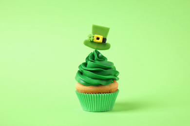 Delicious decorated cupcake on light green background. St. Patrick's Day celebration