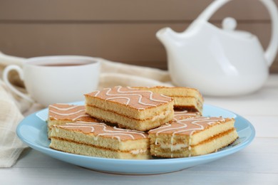 Photo of Tasty sponge cakes and hot drink on while wooden table