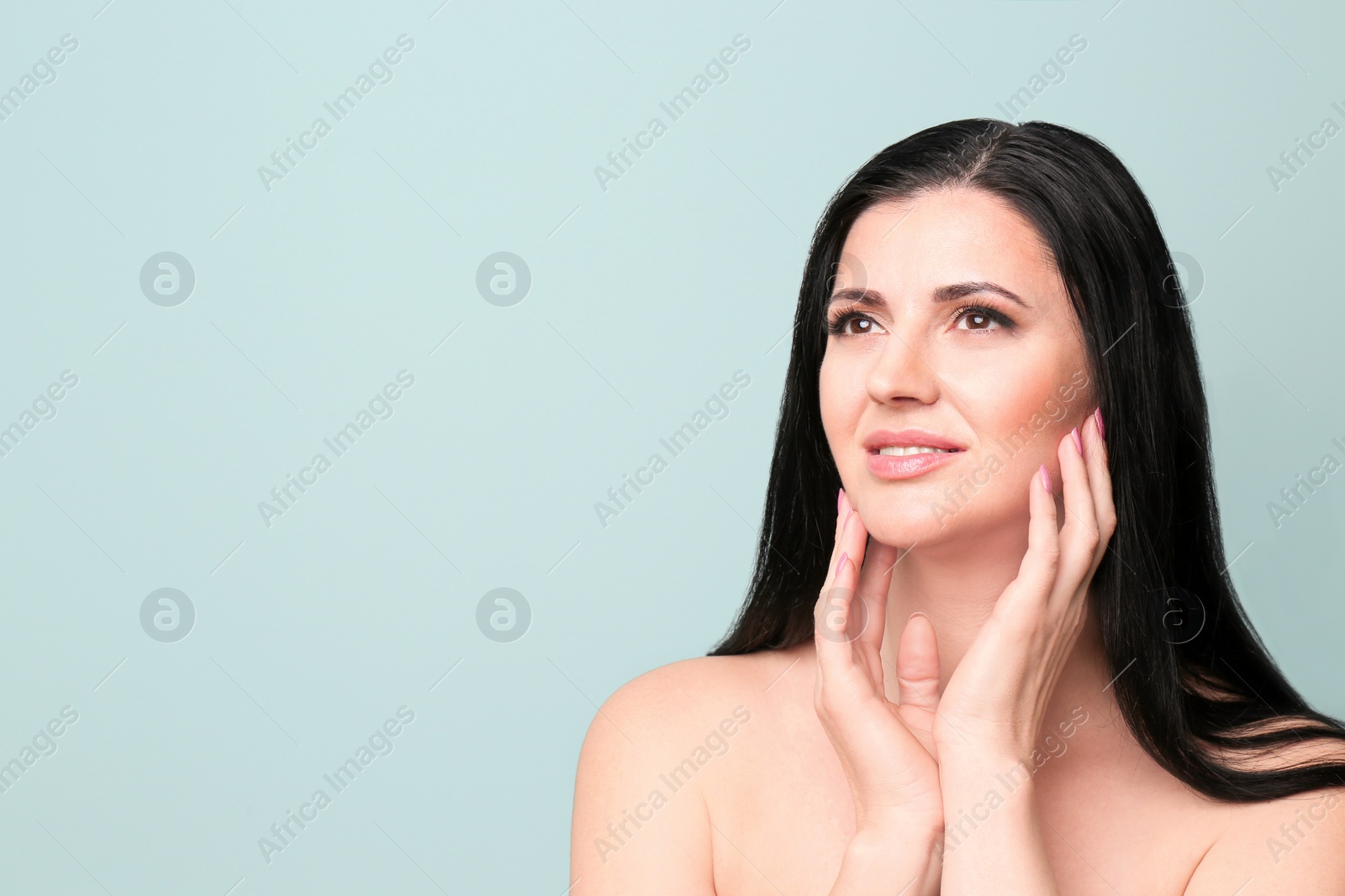 Photo of Beautiful woman with clean skin touching her face on color background