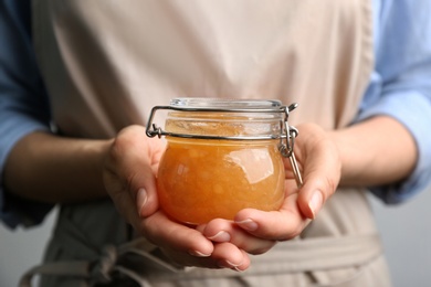Photo of Woman with jar of delicious pear jam, closeup