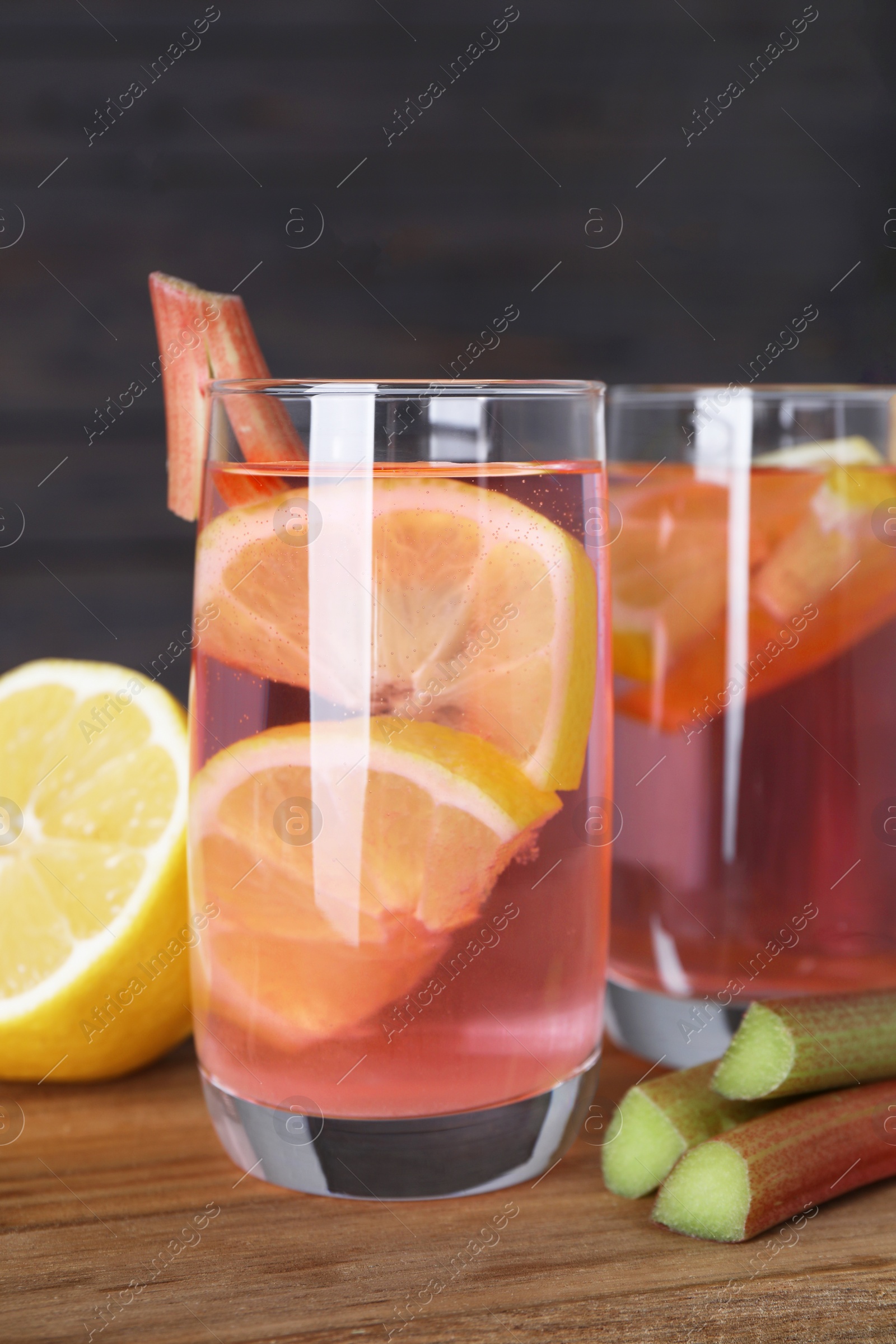 Photo of Tasty rhubarb cocktail with lemon on wooden table, closeup