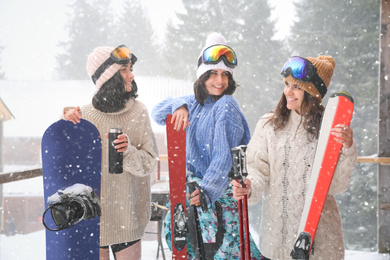 Photo of Friends with sport equipment wearing winter clothes and goggles outdoors