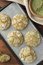 Photo of Baking tray with tasty matcha cookies and powder on wooden table, flat lay