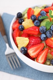 Photo of Delicious fresh fruit salad in bowl served on white table, closeup