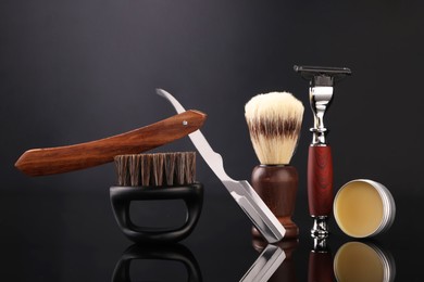 Photo of Moustache and beard styling tools on black mirror surface