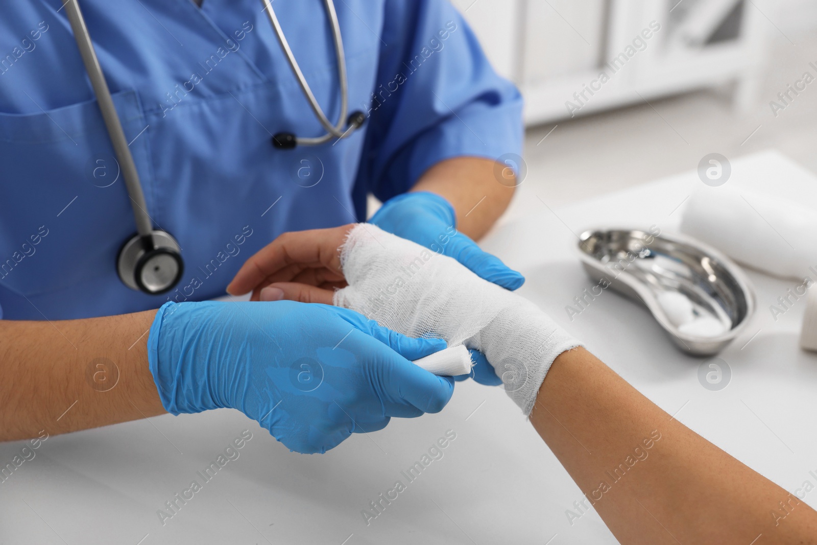 Photo of Doctor bandaging patient's burned hand at table, closeup