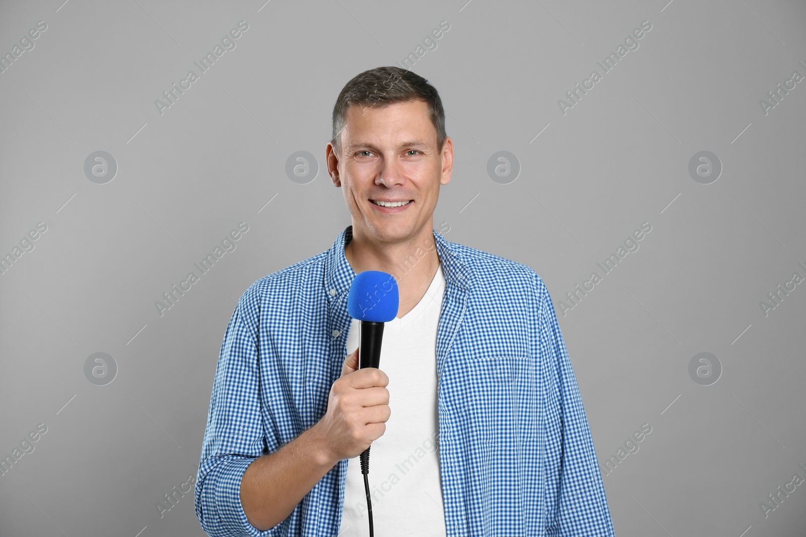 Photo of Male journalist with microphone on grey background