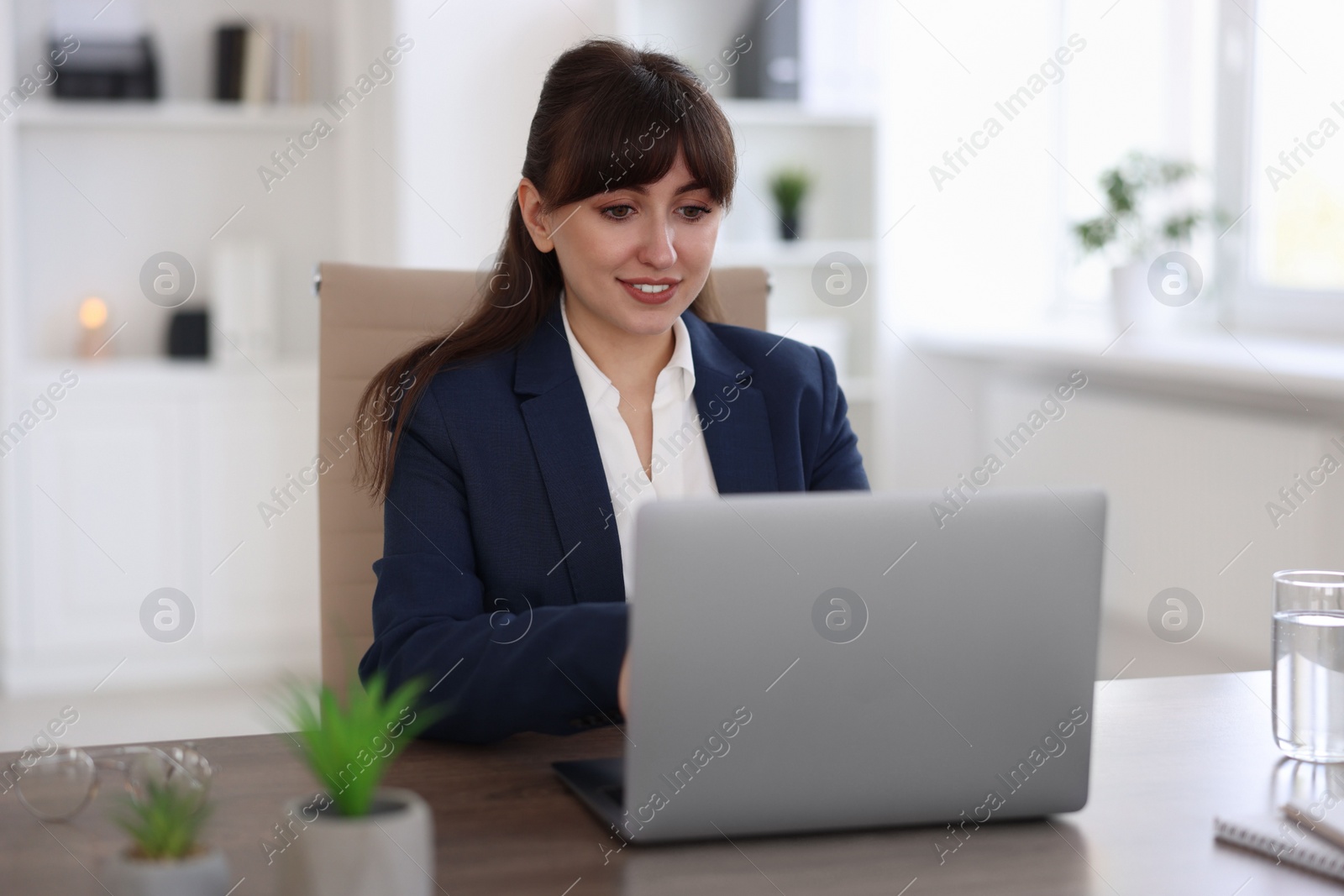 Photo of Woman watching webinar at wooden table in office