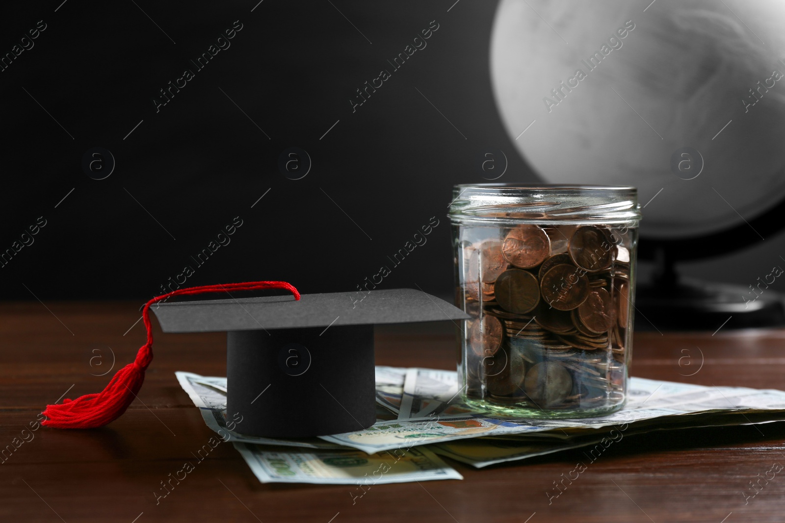 Photo of Scholarship concept. Graduation cap, money and globe on wooden table