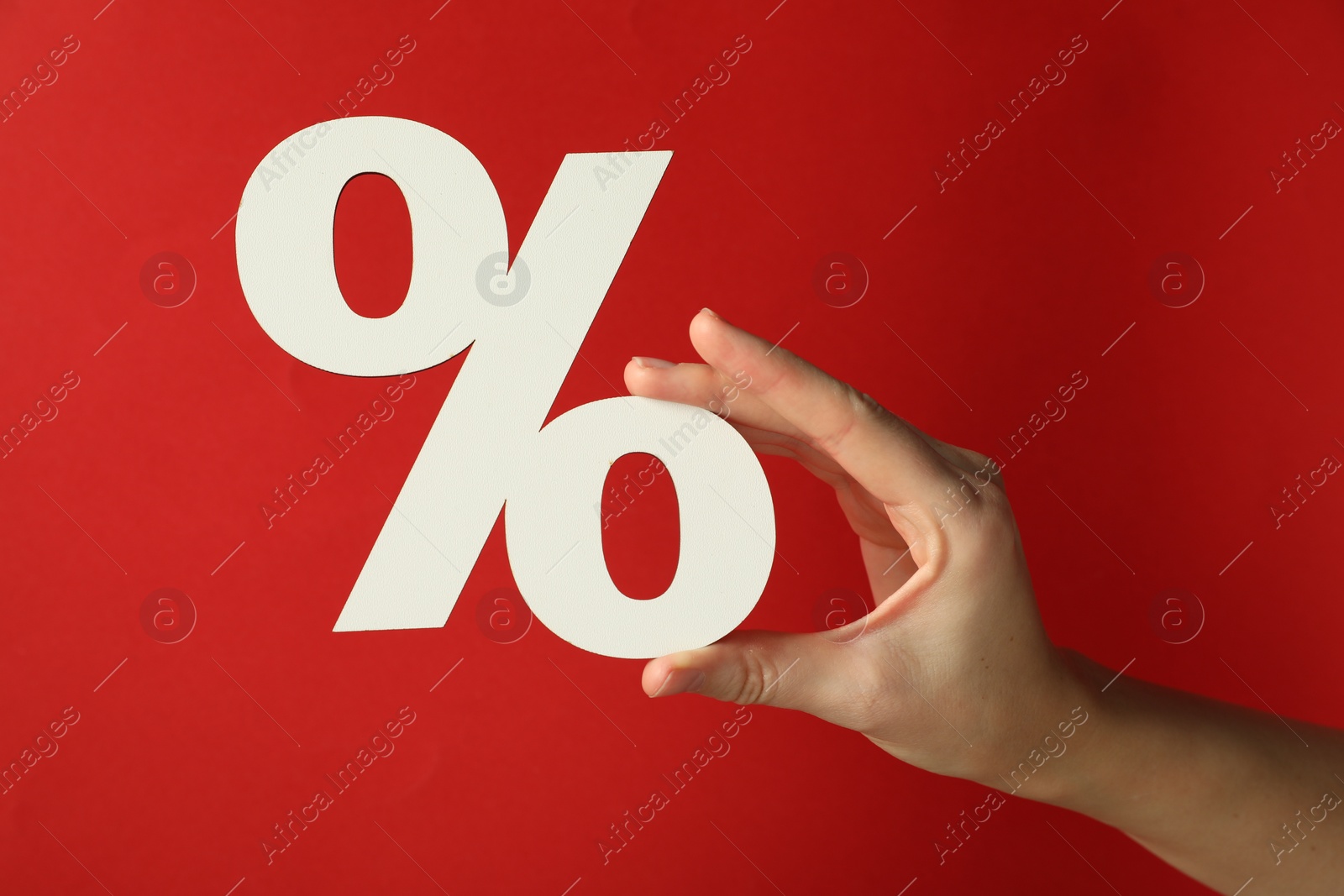 Photo of Woman holding percent sign on red background, closeup