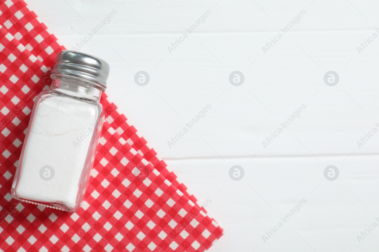 Photo of Salt shaker on white wooden table, top view. Space for text