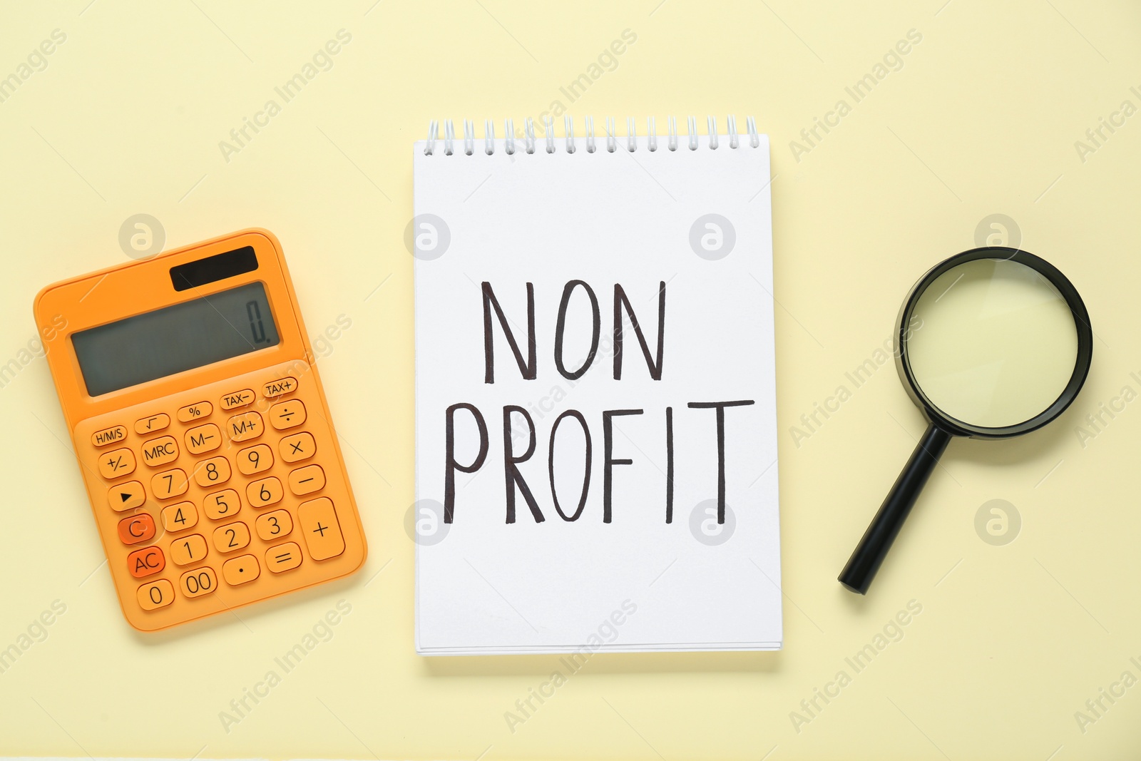 Photo of Notebook with phrase Non Profit, calculator and magnifying glass on beige background, flat lay