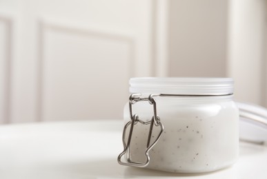 Jar of natural salt scrub on white table. Space for text
