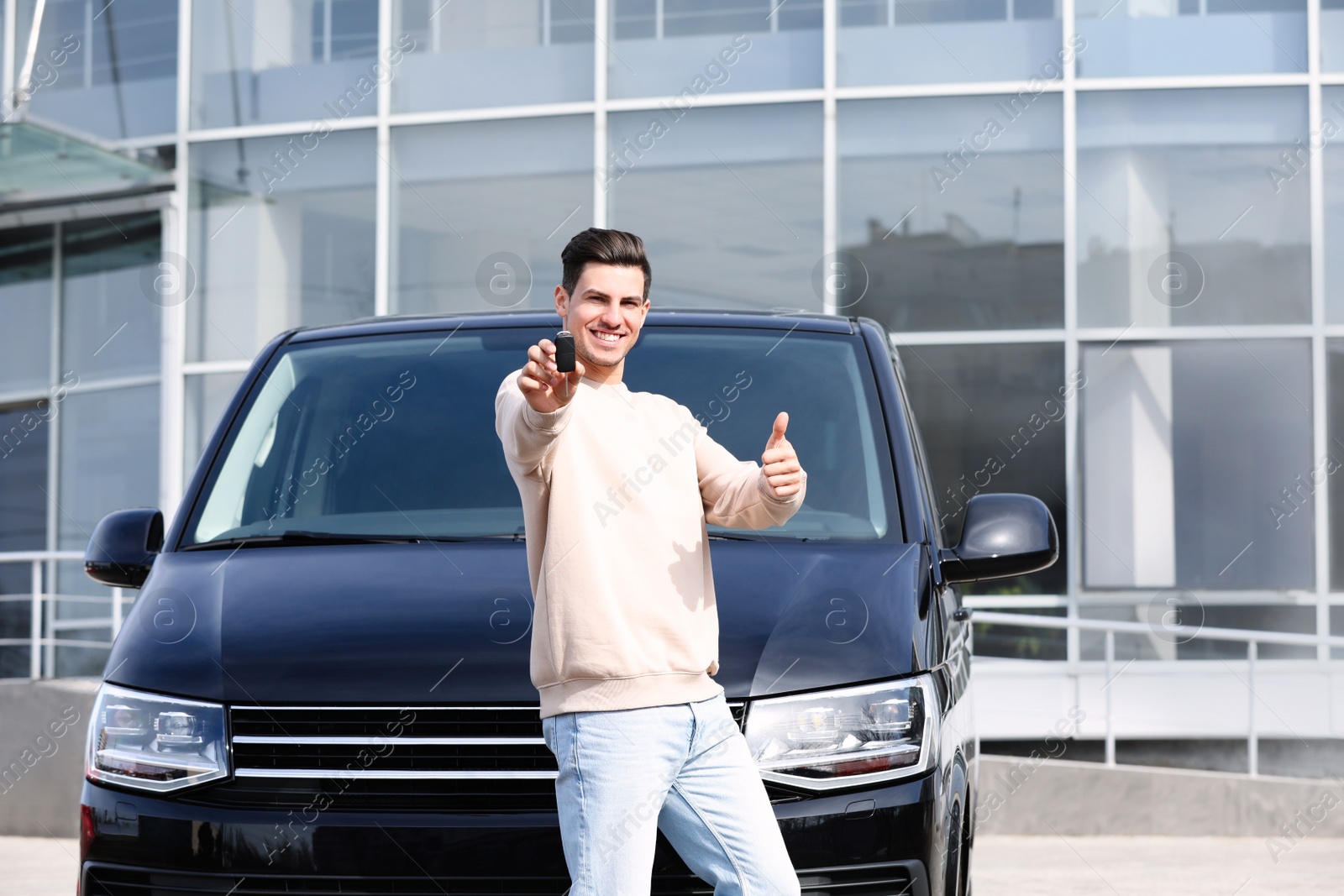 Photo of Man with key near car on city street. Buying new auto