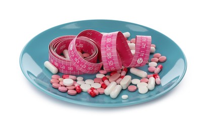 Photo of Plate with weight loss pills and measuring tape on white background