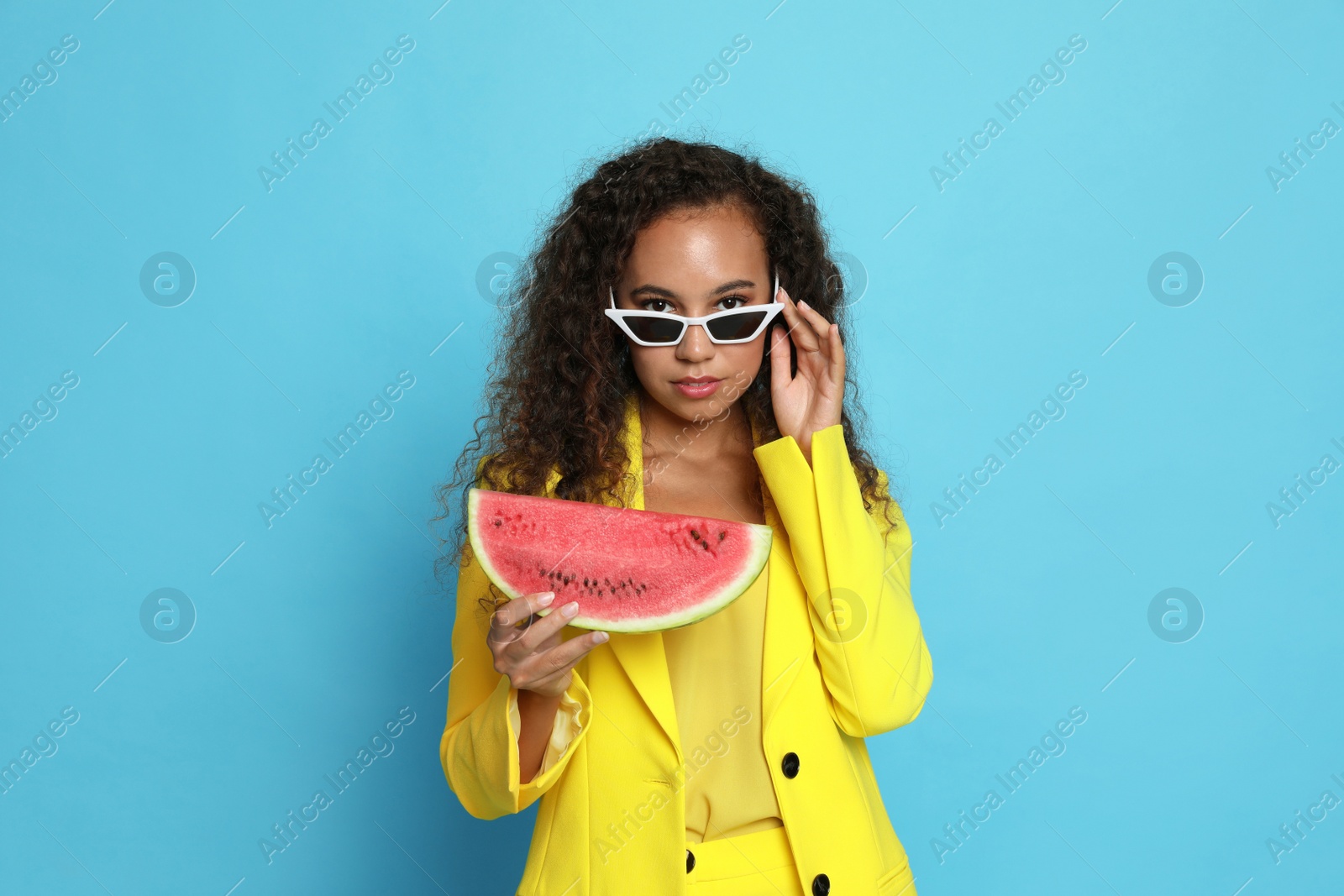 Photo of Beautiful young African American woman with watermelon on light blue background