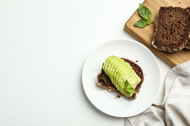 Flat lay composition with avocado sandwich on white table. Space for text